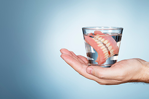 Photo of dentures in a cup of water from  St. Louis Prosthodontics in St. Louis, MO