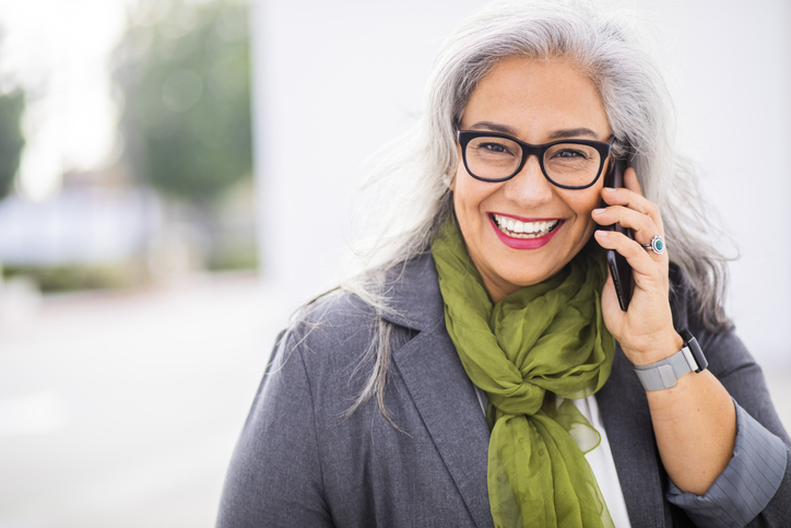 A smiling patient contacting St. Louis Prosthodontics on a cell phone in St. Louis, MO.