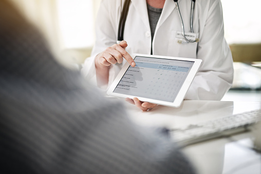 Doctor showing online forms on a digital tablet