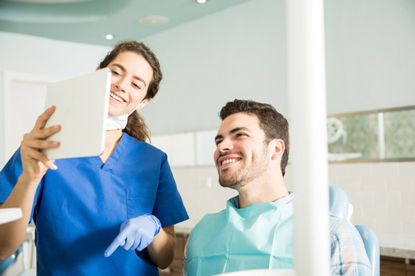 Male patient in dental chair reviewing dental services with dentist in St. Louis office. Male patient in dental chair reviewing dental services with dentist in St. Louis office.