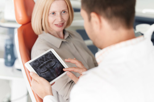 Woman in chair with doctor and x-ray.